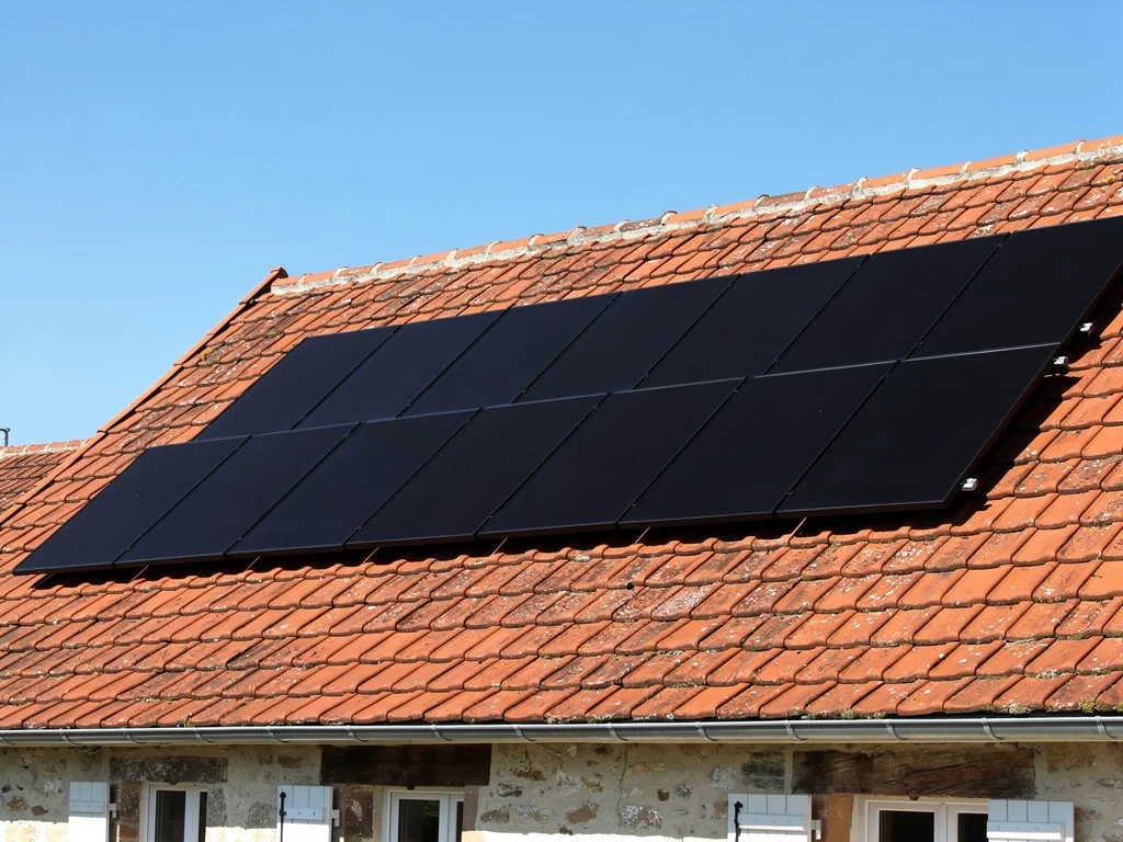 Rangée de panneaux photovoltaïques noirs fixés sur une toiture en tuiles rouges